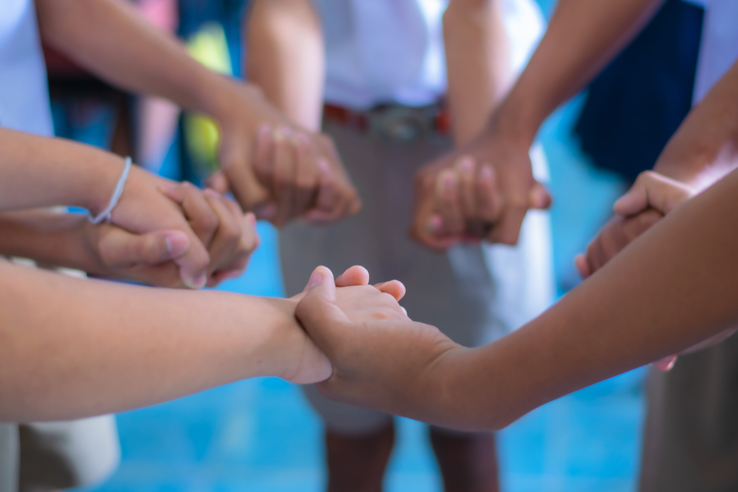 Children are standing, holding hands in a circle to play school